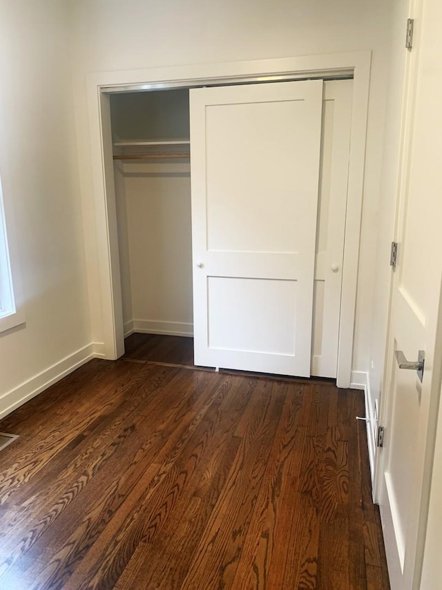 unfurnished bedroom featuring dark hardwood / wood-style floors and a closet