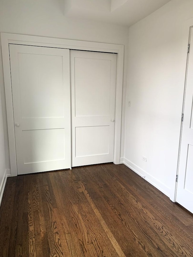 unfurnished bedroom featuring dark hardwood / wood-style flooring and a closet