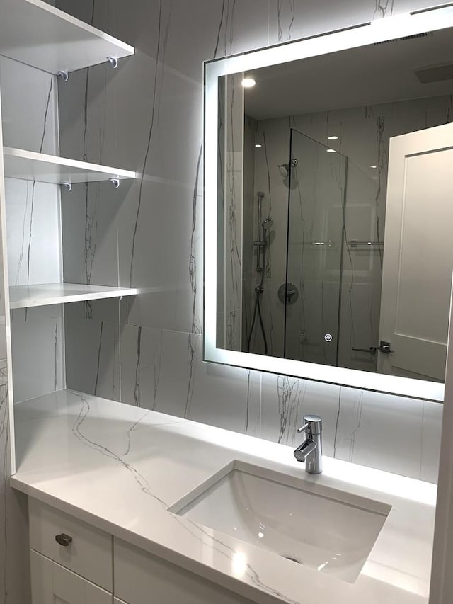 bathroom featuring tiled shower, vanity, and backsplash