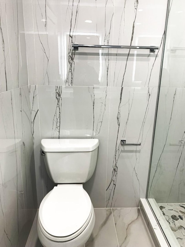 bathroom featuring a tile shower, tile walls, and toilet