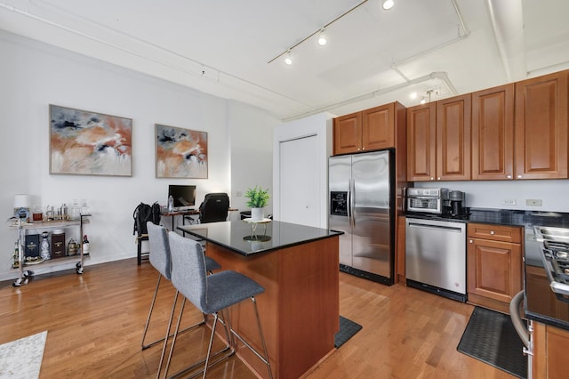 kitchen with light hardwood / wood-style flooring, rail lighting, a breakfast bar, stainless steel appliances, and a center island