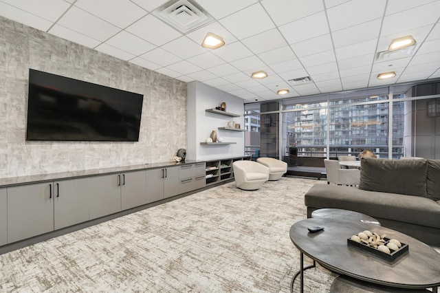 living room with a paneled ceiling and a wall of windows