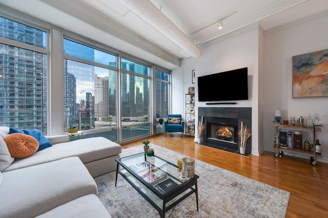 living room featuring expansive windows, a tiled fireplace, hardwood / wood-style floors, and track lighting