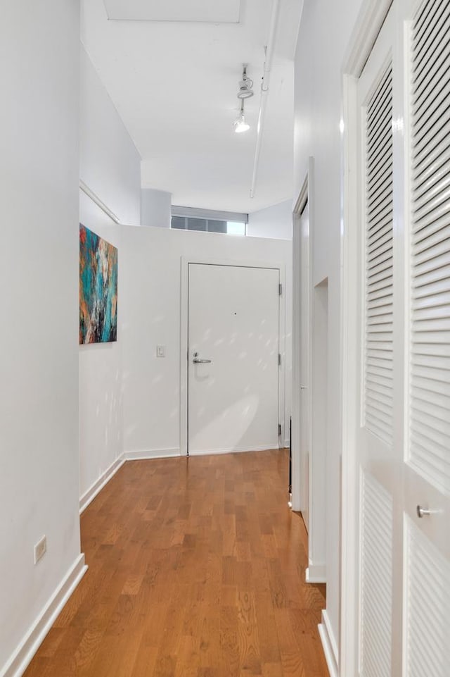 corridor featuring wood-type flooring and track lighting