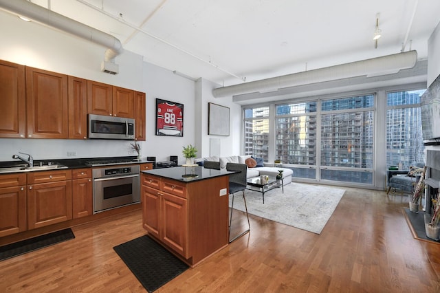 kitchen featuring a kitchen island, rail lighting, sink, stainless steel appliances, and light hardwood / wood-style flooring