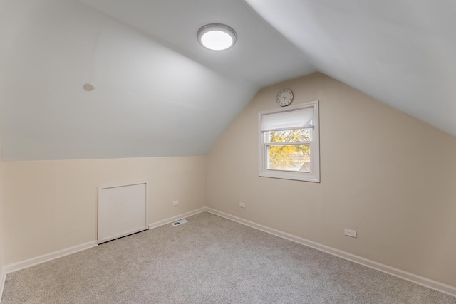 additional living space featuring vaulted ceiling and light carpet