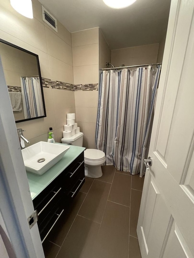 bathroom featuring tile patterned floors, toilet, tile walls, vanity, and curtained shower