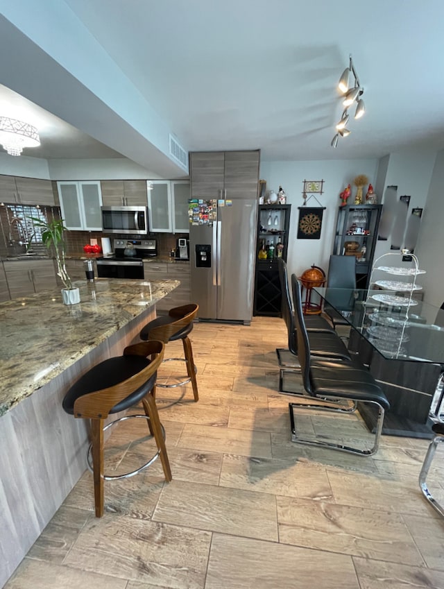 kitchen featuring light stone counters, gray cabinets, and appliances with stainless steel finishes