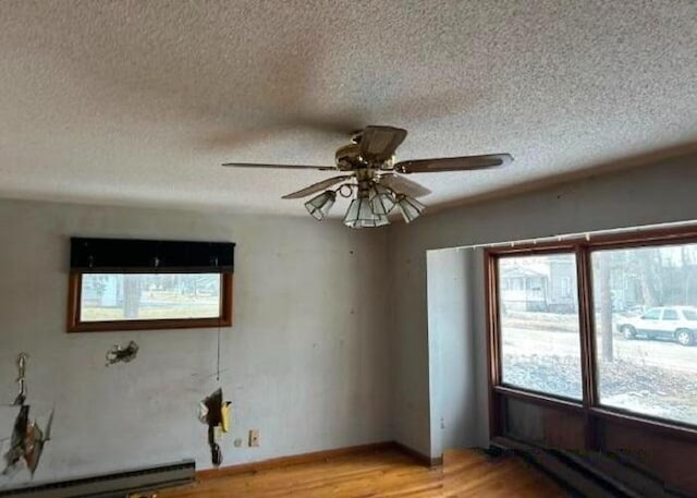 empty room with light hardwood / wood-style floors, ceiling fan, a textured ceiling, and a baseboard radiator