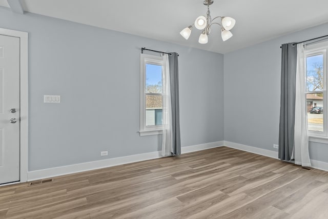 unfurnished room featuring a chandelier and light hardwood / wood-style flooring