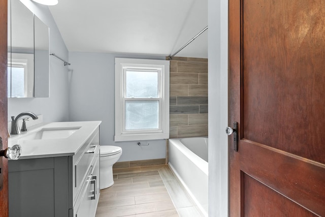 full bathroom with vanity, tiled shower / bath, lofted ceiling, and toilet