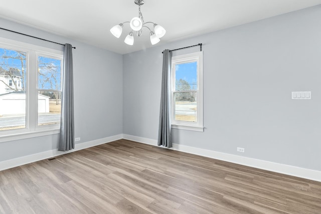 empty room featuring light wood-type flooring and an inviting chandelier