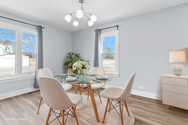 dining area with a notable chandelier and light hardwood / wood-style floors