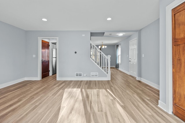 unfurnished room with an inviting chandelier and light hardwood / wood-style floors