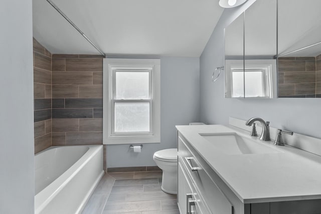 full bathroom featuring tiled shower / bath, vanity, and toilet