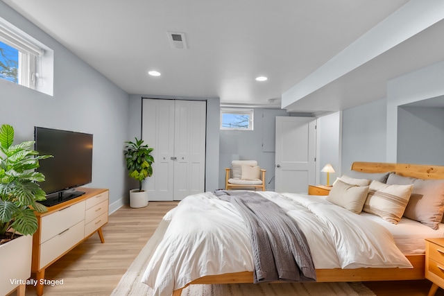 bedroom featuring multiple windows, light wood-type flooring, and a closet