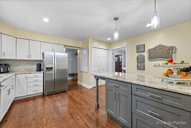 kitchen featuring decorative light fixtures, gray cabinetry, white cabinets, stainless steel fridge, and light stone countertops