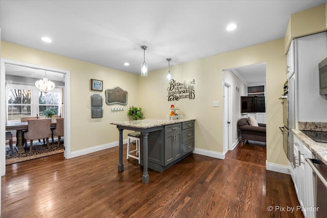 kitchen with gray cabinets, hanging light fixtures, a breakfast bar area, and light stone counters