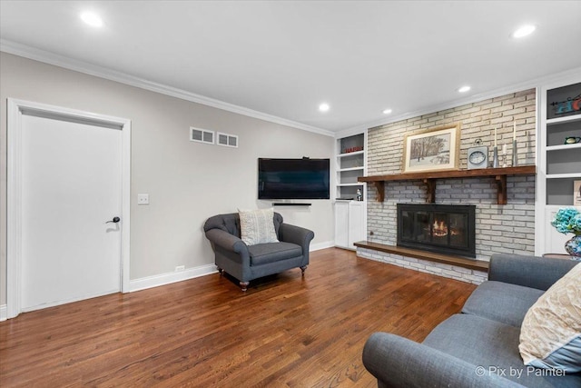 living room with ornamental molding, hardwood / wood-style flooring, a fireplace, and built in features