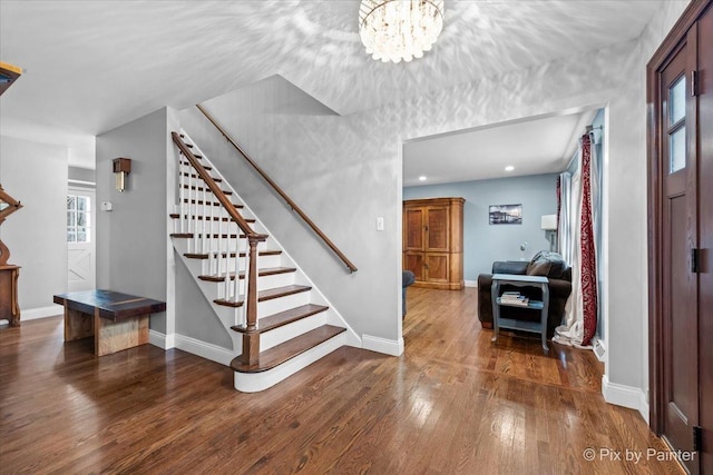 entryway with an inviting chandelier and dark wood-type flooring