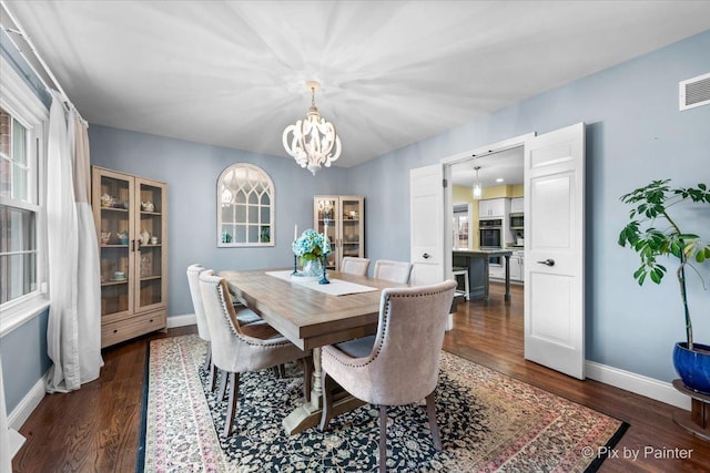 dining area with dark hardwood / wood-style floors and a notable chandelier