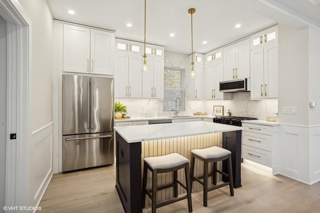 kitchen featuring white cabinetry, sink, stainless steel appliances, and a kitchen island