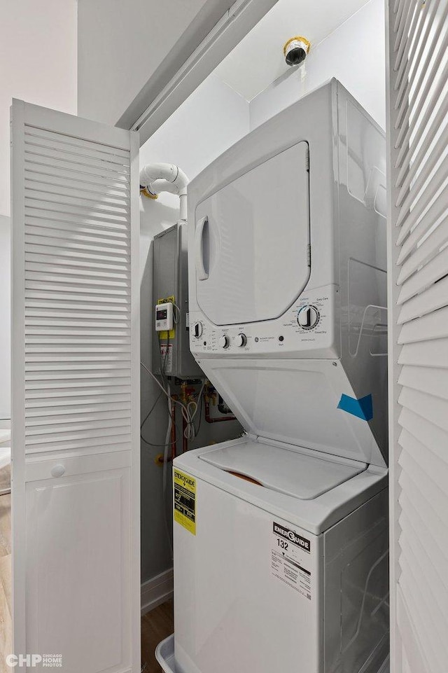 laundry room featuring stacked washer / drying machine and hardwood / wood-style floors