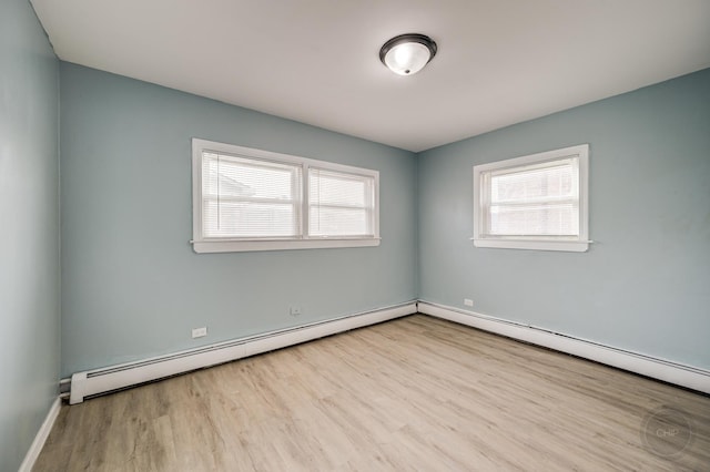 spare room featuring a baseboard heating unit and light wood-type flooring