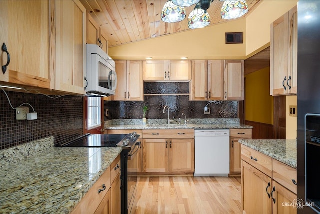 kitchen with white appliances, a sink, visible vents, vaulted ceiling, and light stone countertops