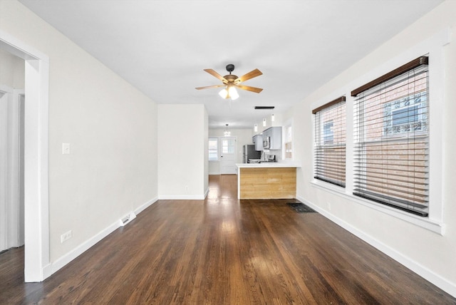 unfurnished living room featuring ceiling fan and dark hardwood / wood-style flooring