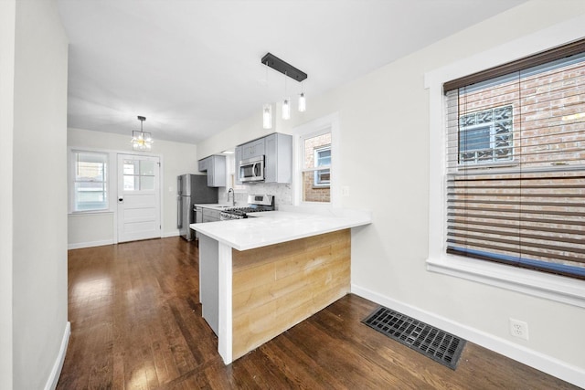 kitchen featuring tasteful backsplash, appliances with stainless steel finishes, dark hardwood / wood-style floors, and kitchen peninsula