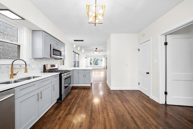 kitchen featuring pendant lighting, sink, gray cabinets, and stainless steel appliances