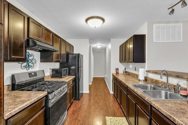 kitchen featuring sink, dark brown cabinets, a textured ceiling, appliances with stainless steel finishes, and hardwood / wood-style flooring