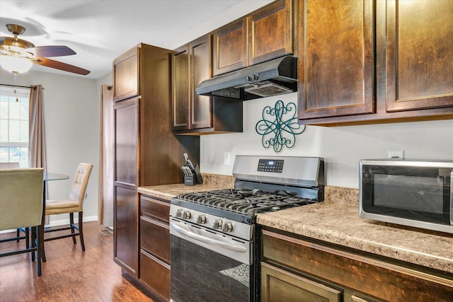 kitchen with dark wood-type flooring, stainless steel range with gas cooktop, and ceiling fan