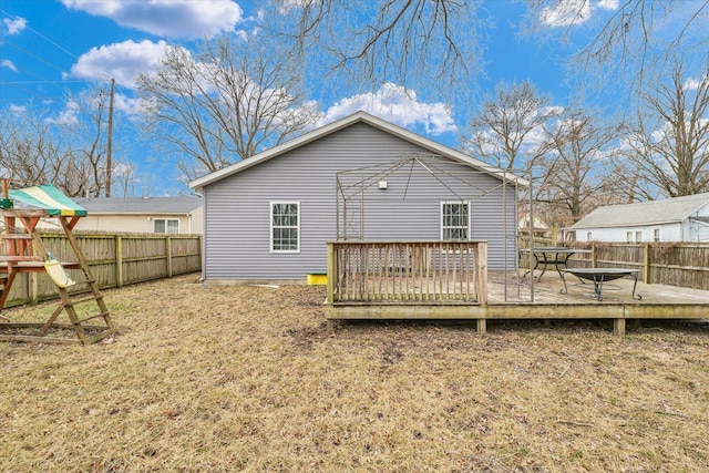 back of house with a lawn, a playground, and a deck