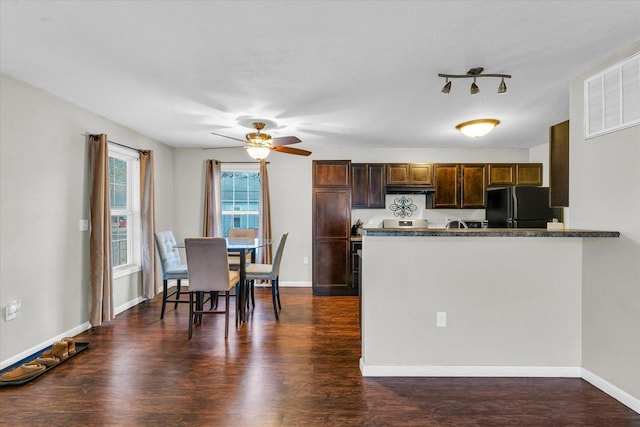 kitchen featuring black refrigerator, dark hardwood / wood-style flooring, kitchen peninsula, and ceiling fan