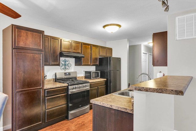 kitchen featuring appliances with stainless steel finishes, sink, and light wood-type flooring