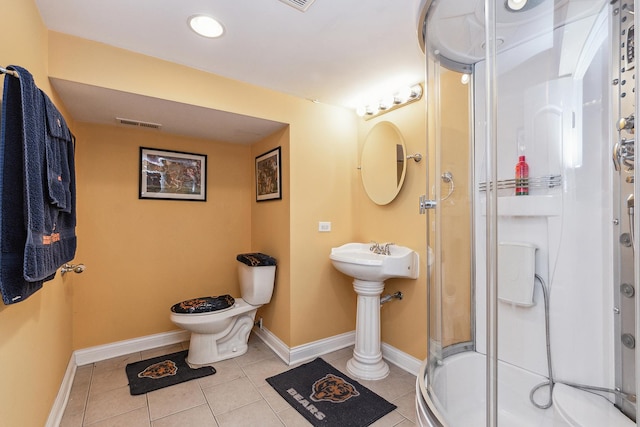 bathroom featuring tile patterned flooring, toilet, and a shower with shower door