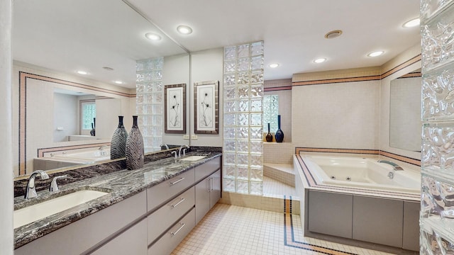 bathroom with tile patterned flooring, vanity, and a relaxing tiled tub