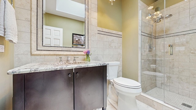 bathroom with toilet, a shower with shower door, tasteful backsplash, tile walls, and vanity