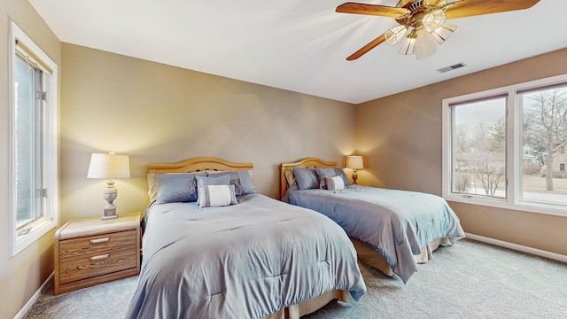 bedroom featuring multiple windows, light colored carpet, and ceiling fan