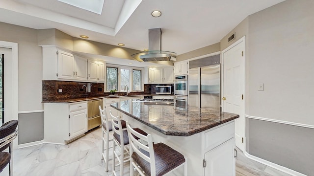 kitchen featuring sink, white cabinetry, island range hood, a center island, and appliances with stainless steel finishes