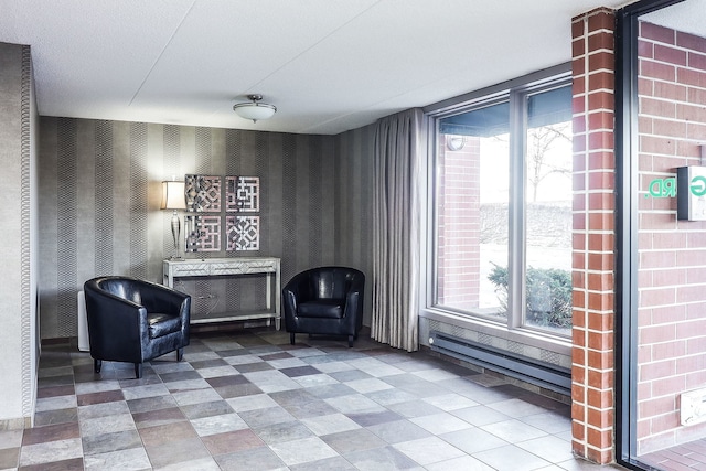 living area featuring a healthy amount of sunlight, baseboard heating, and wallpapered walls