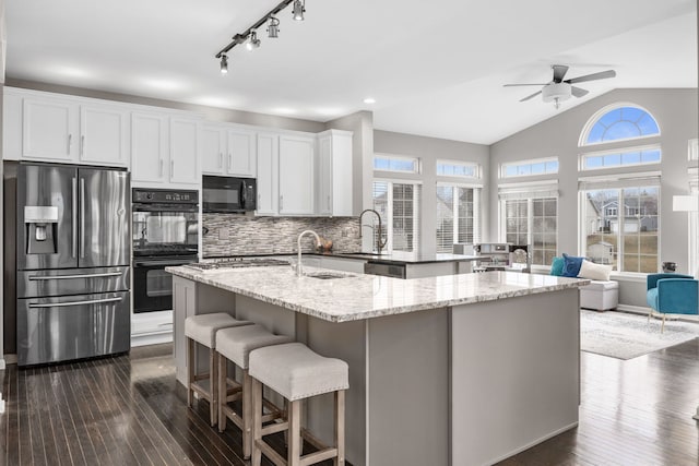 kitchen with dark wood-style floors, a sink, an island with sink, and black appliances