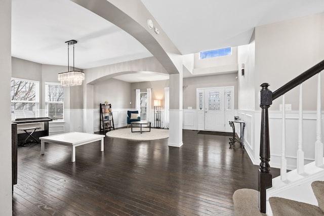 entrance foyer featuring a notable chandelier, a wainscoted wall, visible vents, stairs, and wood-type flooring