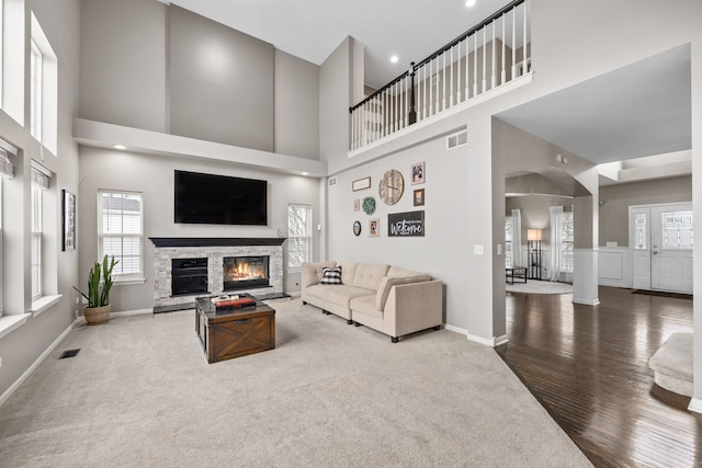 living area featuring carpet floors, a fireplace, visible vents, and baseboards