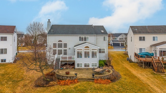 rear view of property featuring a deck, a chimney, a lawn, and stairway