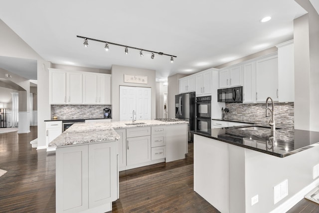 kitchen with dark wood finished floors, a sink, a peninsula, and black appliances