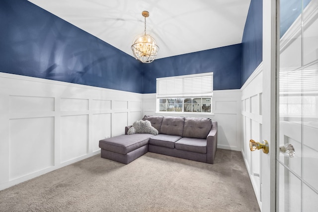 living area with a chandelier, a wainscoted wall, carpet flooring, and a decorative wall