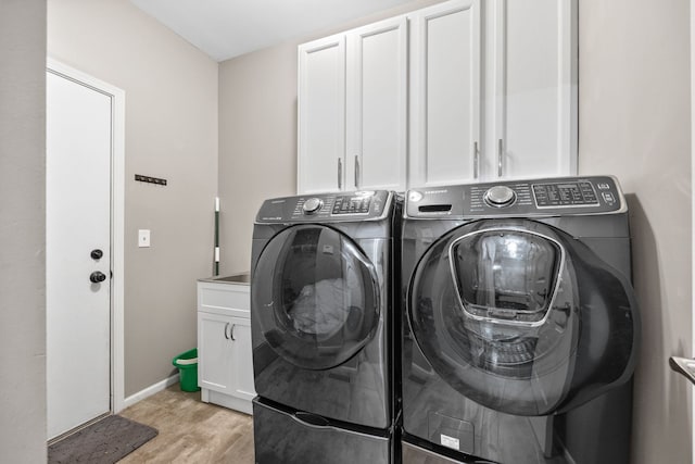 laundry area featuring cabinet space, light wood-style flooring, baseboards, and washer and dryer